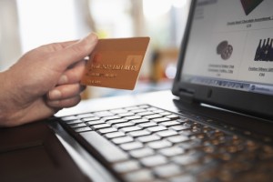 Closeup of woman's hand holding credit card in front of laptop